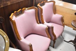 A pair of 19th Century walnut fireside easy chairs having later pink upholstery