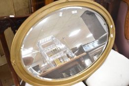 An oval gilt-painted and bevelled mirror, of 1920's design with reed and bead moulding 86cm x 61cm