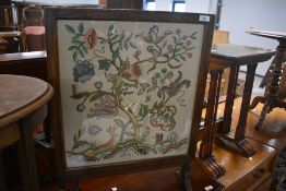 A traditional oak fire screen table having embroidered panel