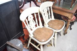 A pair of painted fiddle back kitchen chairs having padded leather seats and turned frames