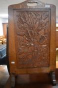 A golden oak fire screen in the Lakeland Arts & Crafts style having carved decoration