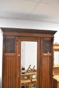 A Victorian mahogany mirror door wardrobe having dentil cornice, urn and foliate carved panel