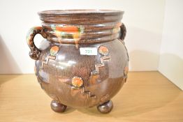 A brown glazed pottery vase decorated with geometrical patterns, two handles and raised on ball