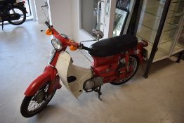 A vintage Honda C90 step through motor cycle in red. YBD225Y (serial No 5183117), first registered