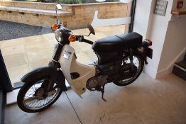 A vintage Honda C90 step through motor cycle in grey. DVU890T (serial No 6131706), first