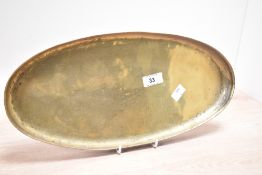 An early 20th-century Arts and Crafts hammered brass oval tray by Hugh Wallis, marked to front, 38cm