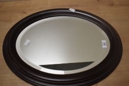 A 20th-century mahogany wall hanging mirror, of oval design, 48cm in height.