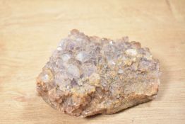 A raw amethyst geode cluster, featuring lighter translucent areas that transition to a deeper violet