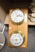 A 20th-century German ship’s brass clock with barometer, mounted on a wooden board, 53.5cm,