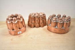 Three Victorian copper jelly moulds of varying designs, comprising: two with round fluted or