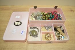 A vintage pink plastic jewellery box with a cameo to lid, containing a small assortment of costume