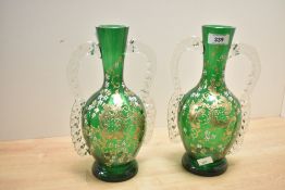 Two Victorian green glass vases, featuring enamel and gilt floral decoration, with two handles, 26.