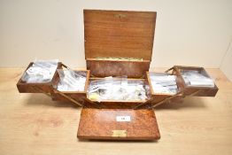 A wooden jewellery box having extendable shelves, containing an assortment of costume jewellery