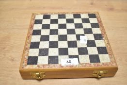 A 20th-century stone chess set, with a contrasting stone board, hinged lid and 32 pieces, the