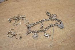A silver charm bracelet having a padlock clasp and seven charms including football boots and