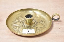 A vintage brass Arts and Crafts decorated chamber stick, featuring an embossed floral pattern,