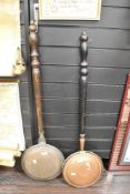 Two 20th-century bed warming pans, one brass and one copper, both with turned wooden handles, the