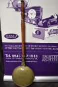 An antique brass bed warming pan with a turned wood handle, measuring 108cm, the base of the pan has