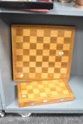 A 20th-century wooden folding chessboard with accompanying stylised African Art chess pieces, hand-