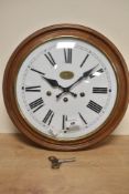 A 20th-century reproduction oak wall clock of circular form with Roman hours by Guernsey Clockmakers
