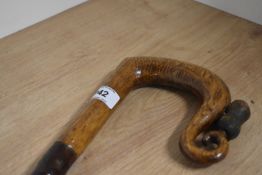 A wooden walking stick with wooden crook carved handle with a thistle carved to the handle tip and