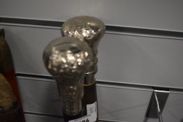 Two thick sectional walking canes with white metal tops