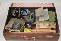 A small vintage suitcase containing a mixture of vintage fishing tackle and spinning reels