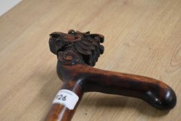 A carved wooden walking stick depicting a dragons head with loose ball in its mouth and oriental
