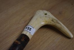 A twisted wooden walking stick with an antler top and an eye being added to give the impression of a