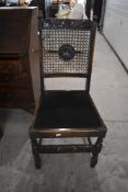 An early 20th Century oak framed carver chair having bergere cane back (af) and a matching dining