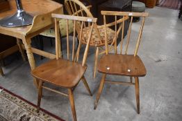 A pair of 1960's Ercol spindle back chairs, having three central spindles, solid seats and turned