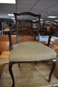 An early 20th Century mahogany framed carver chair having scroll arms and shaped ladder back