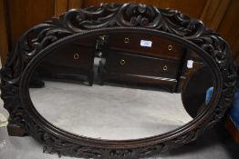 A decorative carved oak wall mirror, of oval form with carved and pierced foliate scrolls, 67cm x