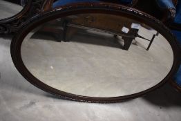 A 1920's style oval wall mirror with bevelled plate 58cm x 82cm overall