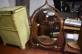 An Edwardian mahogany swing toilet mirror, of oval form pivoted between a shaped surround 73cm