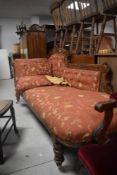 A late Victorian oak framed chaise longue, of traditional design with scrolled arm and buttoned