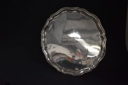 A George V silver salver, of circular form having a lobed moulded rim, raised on three cabriole