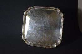 A George VI silver salver, of square form having lobed corners, raised on four scroll feet, marks