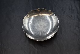 A George VI silver pin dish, of circular form depicting a lotus flower, raised on four ball feet,