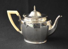 A late George V silver teapot, of oval form having canted sides, a curved spout opposed by an