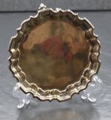 A George V silver salver, of circular form having a Chippendale style rim, raised on three scroll