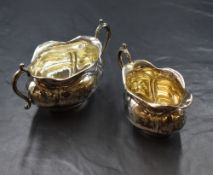 A pair of early George V silver sugar and cream, of oval form having slightly flared rims and canted