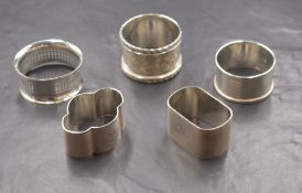 A group of five silver napkin rings, of various form including scroll decoration, engine turned