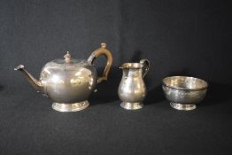 A George V silver three-piece tea set, comprising a teapot, sugar and cream, having decorative
