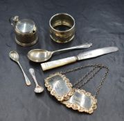 An assortment of silver items, comprising two decanter labels, a napkin ring, a mustard with blue