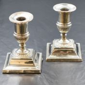 A pair of Edwardian silver candlesticks, of traditional form having circular sconces with bead