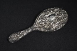 A Victorian silver mounted hand mirror, of oval form having embossed scroll and diaper decoration