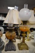 Two Victorian oil lamps, comprising one with an ornate cast iron base, milk glass body, and clear