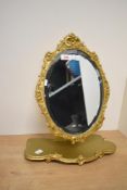 A mid to late 20th-century Peerart Rococo-style gilded resin oval mirror, fitted to a stand,