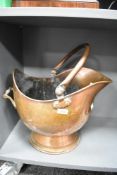 A large late 18th to 19th-century copper coal scuttle of helmet form, featuring a swing carrying